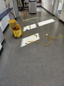 A yellow bucket and mop on the floor of a kitchen.
