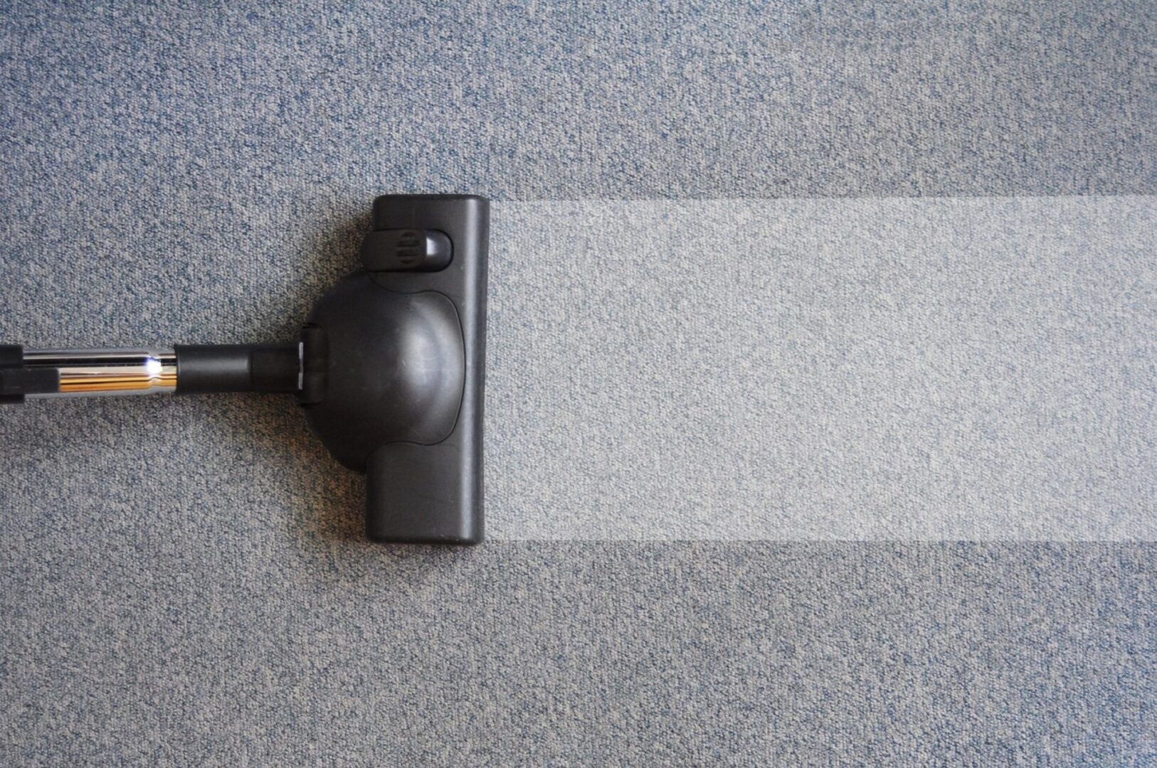 A vacuum cleaner is on the floor with its head down.