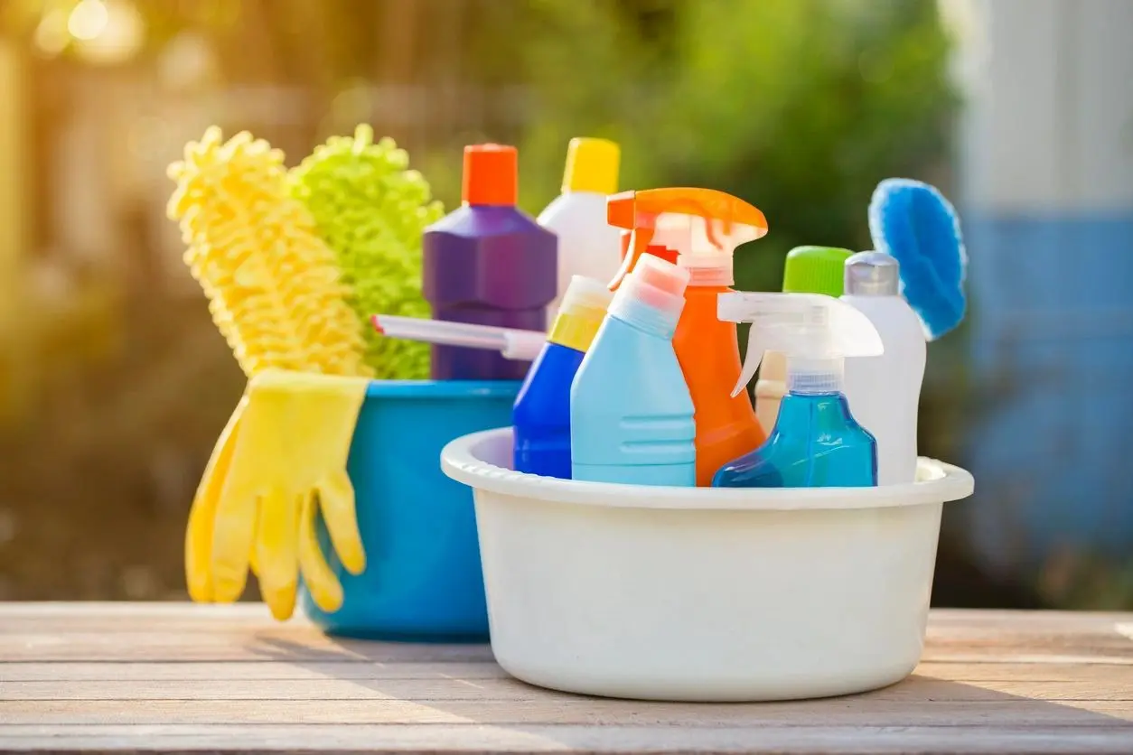 A bowl of cleaning supplies and gloves on the table.