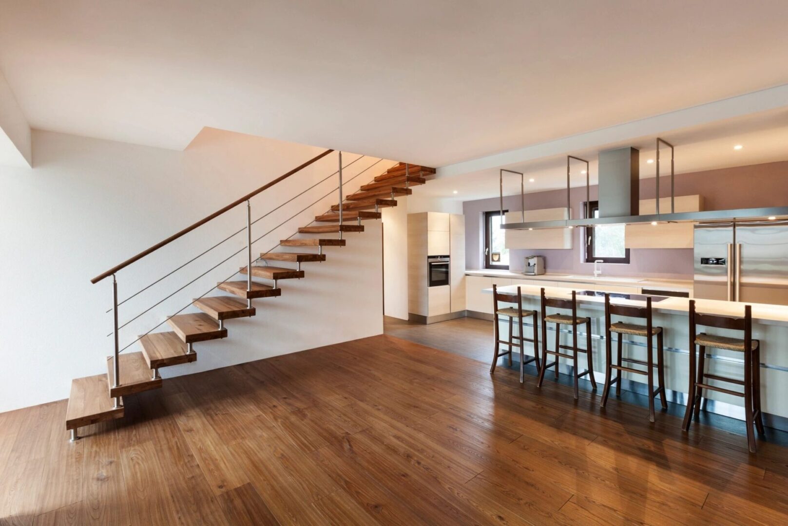 A room with wooden floors and stairs leading to the top floor.