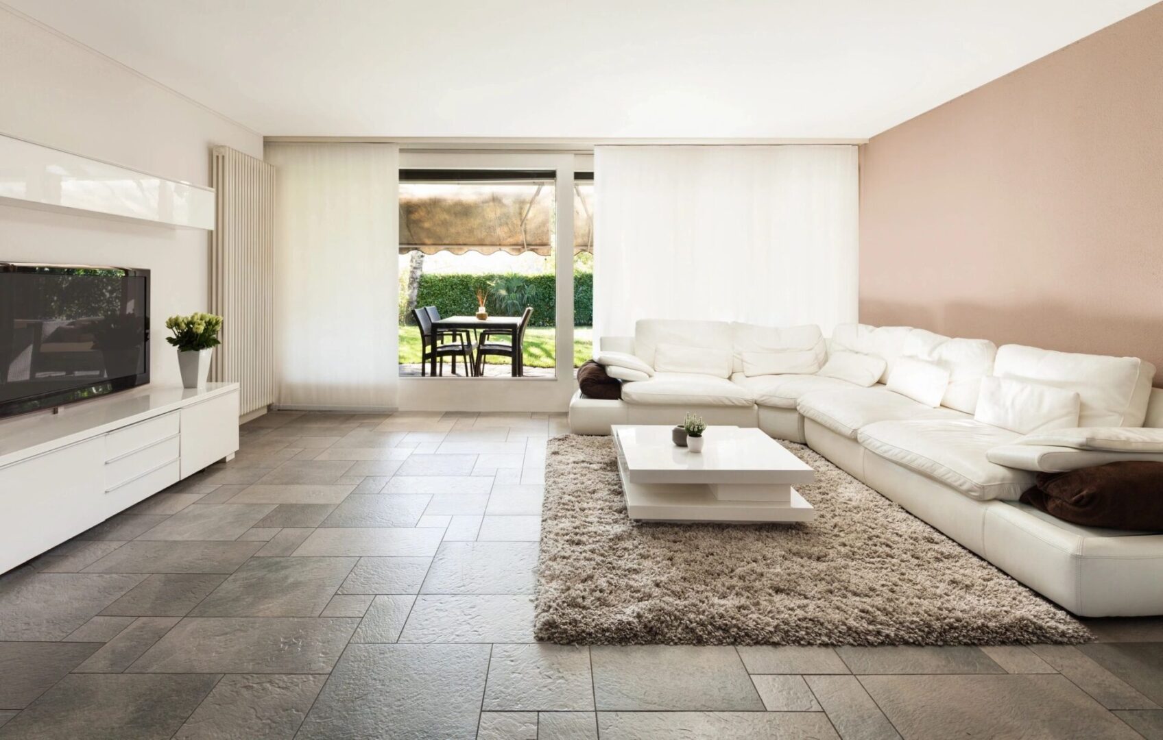 A living room with white furniture and tile floors.